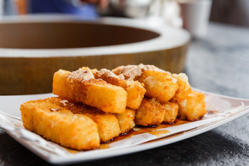 A plate of glutinous rice cake dipped in melted brown sugar with on a stone table in a restaurant