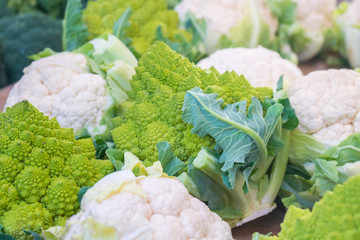 fresh cauliflower with white heads and green leaves at weekly market