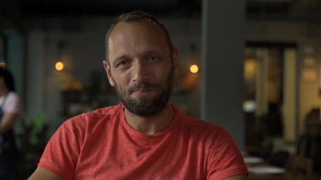 Young, happy man drinking cocktail sitting in cafe