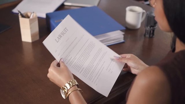 Beautiful woman write and sign lawsuit at the office of lawyer. With support of good solicitor, testimonies and witness female convinced to make justice and execute process against illegal financial