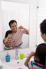father and daughter brushing teeth together