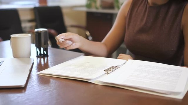 Close up african-american lawyer verifying contract making stamp. Legal professional checking notary document and using stamper for validation.