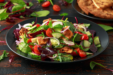 Traditional fattoush salad on a plate with pita croutons, cucumber, tomato, red onion, vegetables...
