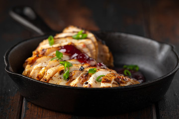 Grilled sliced chicken breast with cranberry sauce in mini cast iron frying pan