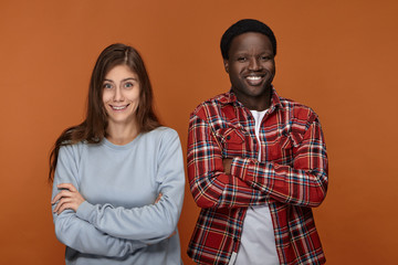 Fototapeta premium Positive human emotions, feelings, reaction and attitude. Funny cute white woman with loose hair posing in studio with her black man, having clueless, confused or surprised facial expressions, smiling
