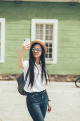 Pretty brunette woman internet blogger talking by smartphone in old city