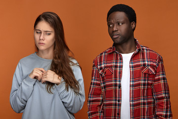 Frustrated European 20 year old girl feeling nervous because of disagreement with her dissapointed displeased African American boyfriend. People, ethnicity, relationships, quarrel and problems concept