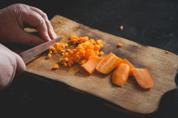 Woman cutting carrot on table, closeup