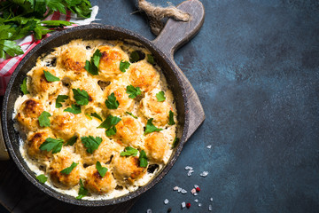 Meatballs in cream sauce on dark stone table top view.