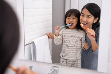 mom and kid brushing their teeth together