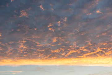 Dramatic sky covered in clouds colored by morning light