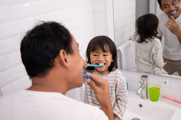 kid learn how to brush teeth with dad