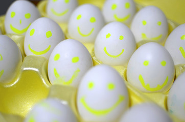 Group of eggs with drawn emotions. White chicken eggs in a cardboard package, with cartoon faces. background, texture