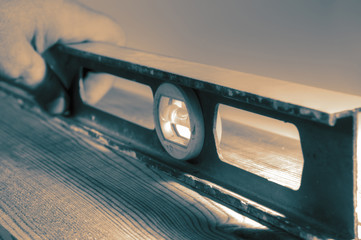 Man using a spirit level on a plank of wood with colour toning