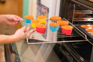 Closeup photo of woman putting cookies in oven. Woman puts in the oven cookies in the forms