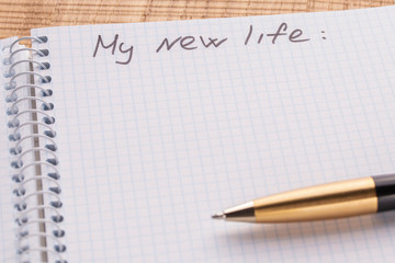Top view workplace notebook and pen on wood table background. Inscription - my new life