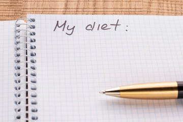 Top view workplace notebook and pen on wood table background, retro effect. Inscription - My diet.