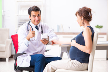 Fototapeta premium Young doctor checking pregnant woman's blood pressure