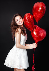 Happy beautiful woman with red balloons over black background. Happy Valentines day on international womans day.