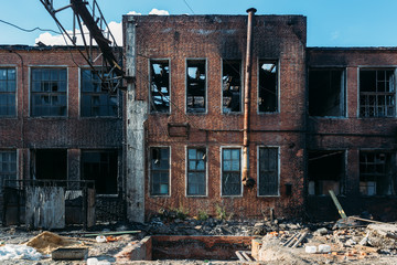 Fototapeta premium Consequences of fire. Burnt industrial or office building of red brick. Broken windows, walls in black soot