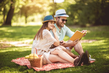 Beautiful couple enjoying picnic time outdoor reading book
