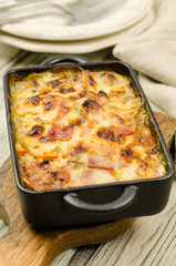 Potato gratin with parmesan cheese, cream and cured bacon from South Tyrol. Tartiflette: baked potatoes with bacon and cheese close up. Scalloped potato casserole 