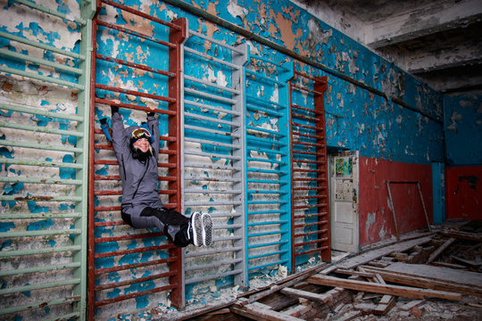 Lonely kid girl in abandoned old children school, oldish walls with cracked paints yellow blue green walls, forsaken strange left out deserted scenery, film look, atmospheric light of empty rooms