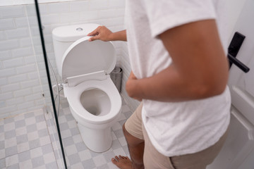 man hold his stomach painful in the toilet