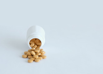 Round beige tablets poured out of the jar. On a white background.