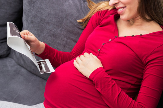 Pregnant woman looking at ultrasound image of her baby