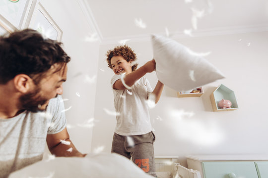 Boy playing with his father at home with pillows