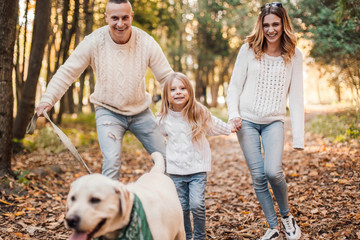 Obraz premium Happy family is having fun with dog labrador outdoors.