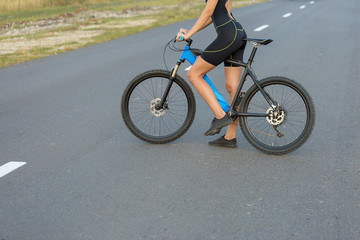 Naklejka premium A girl riding a mountain bike on an asphalt road, beautiful portrait of a cyclist at sunset 