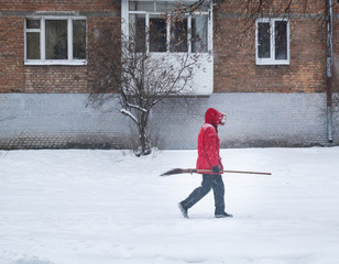 man in red coat with long broom