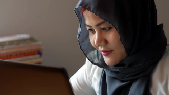 Muslim Lady Smiling Happy While Typing Online Chat on Laptop