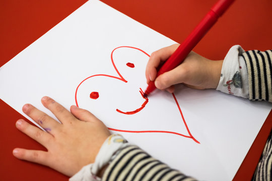 Child drawing a smiling heart