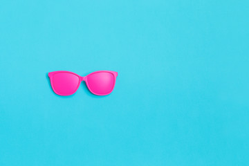 Pink glasses on blue background. Minimal concept. Creative concept. Hot Summer. Pop Art. Bright Sweet fashion Style.