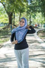 Happy face, young Asian woman with tudung or hijab smile and standing at green park.