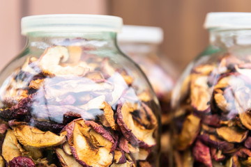 Dehydrated pink purple colorful dry homemade apple fruit slices stored in many glass jars macro closeup