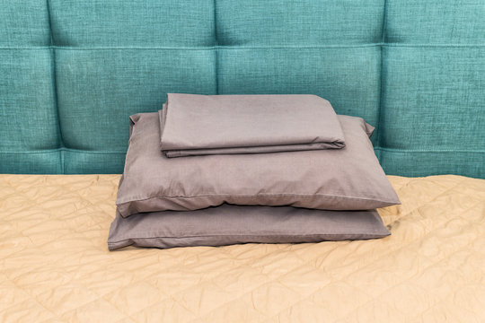 Hotel bed with green blue headboard and pillows in bedroom in home house or apartment with sheets stack closeup