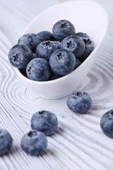 Ripe and sweet blueberries on a textured wooden table in a beautiful white ceramic Cup