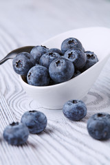 Ripe and sweet blueberries on a textured wooden table in a beautiful white ceramic Cup
