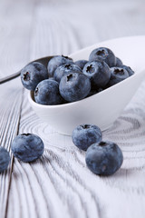 Ripe and sweet blueberries on a textured wooden table in a beautiful white ceramic Cup