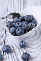 Ripe and sweet blueberries on a textured wooden table in a beautiful white ceramic Cup