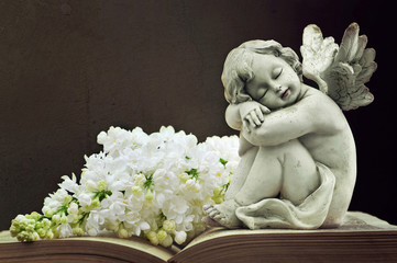 Angel and white lilac flower on old book