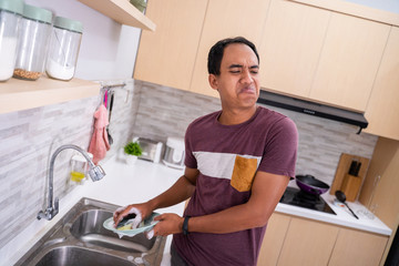 unhappy man while washing dishware