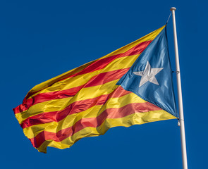 Catalan flag in support of the independence of Catalunya flies above Girona with blue sky background