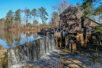 Scenic winter view of the waterfall and dam by the old gristmill at Historic Yates Mill County Park in Raleigh North Carolina. Icicles hand from the flume and waterwheel.