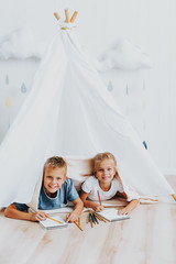Two cute children drawing together in wigwam © Yakobchuk Olena