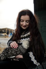 Fototapeta premium Long haired girl on a farm cuddles a fluffy chicken